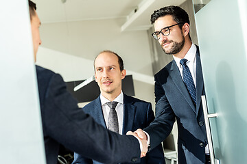 Image showing Group of confident business people greeting with a handshake at business meeting in modern office or closing the deal agreement by shaking hands.