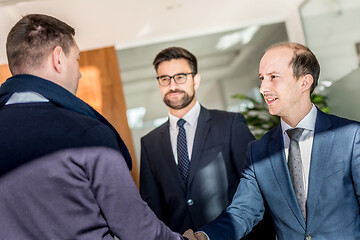 Image showing Group of confident business people greeting with a handshake at business meeting in modern office or closing the deal agreement by shaking hands.