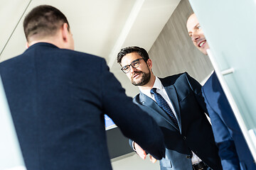 Image showing Group of confident business people greeting with a handshake at business meeting in modern office or closing the deal agreement by shaking hands.