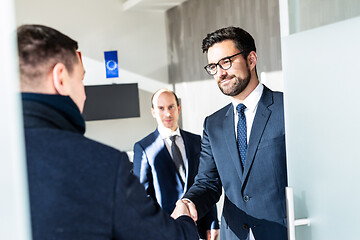 Image showing Group of confident business people greeting with a handshake at business meeting in modern office or closing the deal agreement by shaking hands.
