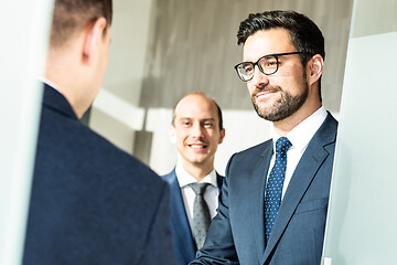 Image showing Group of confident business people greeting with a handshake at business meeting in modern office or closing the deal agreement by shaking hands.