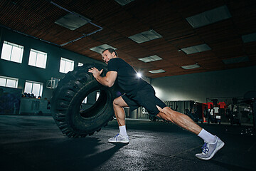 Image showing Shirtless man flipping heavy tire at gym