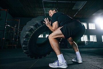 Image showing Shirtless man flipping heavy tire at gym