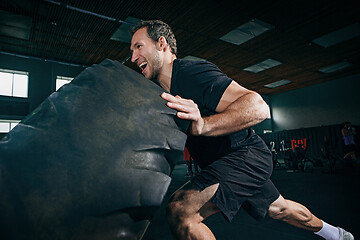 Image showing Shirtless man flipping heavy tire at gym