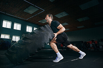 Image showing Shirtless man flipping heavy tire at gym