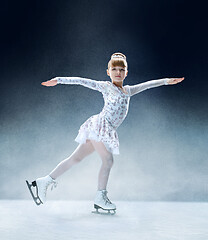 Image showing Little girl figure skating at the indoor ice arena.