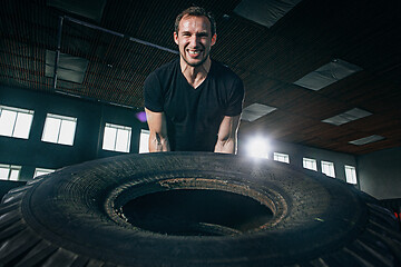 Image showing Shirtless man flipping heavy tire at gym