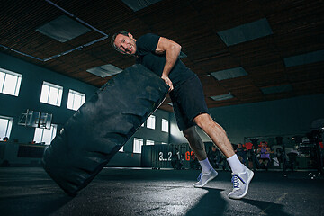 Image showing Shirtless man flipping heavy tire at gym