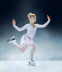 Image showing Little girl figure skating at the indoor ice arena.
