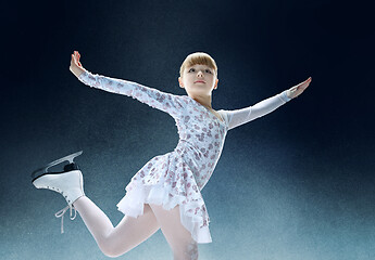 Image showing Little girl figure skating at the indoor ice arena.