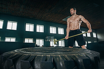 Image showing Shirtless man flipping heavy tire at gym