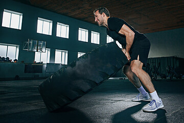 Image showing Shirtless man flipping heavy tire at gym