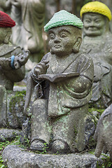 Image showing Old stone statue of Buddhist monk wearing knitted hat with book in his hands.