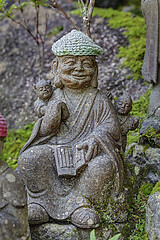 Image showing Old stone statue of Buddhist monk wearing knitted hat with book in his hands.