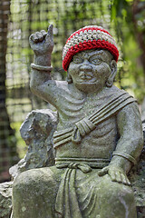 Image showing Old stone statue of Buddhist monk wearing knitted hat pointing the finger up.