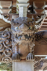 Image showing Wooden carving of an angry Komainu decorates the gable of a roof over the entrance of an ancient Buddhist temple in Japan.