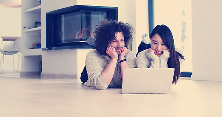 Image showing young multiethnic couple using a laptop on the floor