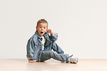 Image showing The portrait of cute little boy in stylish jeans clothes looking at camera at studio