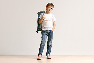 Image showing The portrait of cute little boy in stylish jeans clothes looking at camera at studio