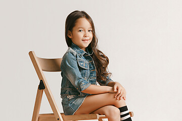 Image showing The portrait of cute little kid in stylish jeans clothes looking at camera and smiling