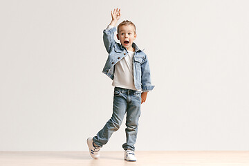 Image showing The portrait of cute little boy in stylish jeans clothes looking at camera at studio