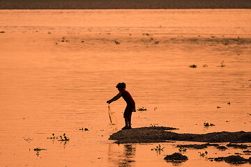 Image showing Asian Woman fishing in the river, silhouette at sunset