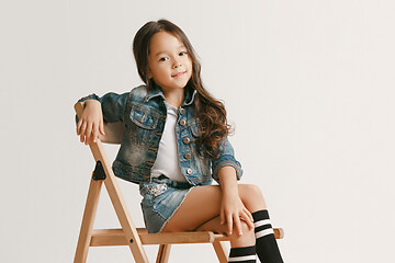 Image showing The portrait of cute little kid in stylish jeans clothes looking at camera and smiling