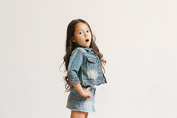 Image showing The portrait of cute little kid in stylish jeans clothes looking at camera and smiling