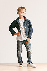 Image showing The portrait of cute little boy in stylish jeans clothes looking at camera at studio