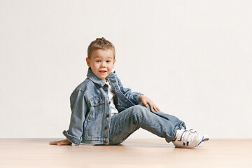 Image showing The portrait of cute little boy in stylish jeans clothes looking at camera at studio