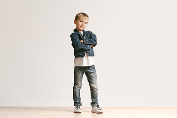 Image showing The portrait of cute little boy in stylish jeans clothes looking at camera at studio