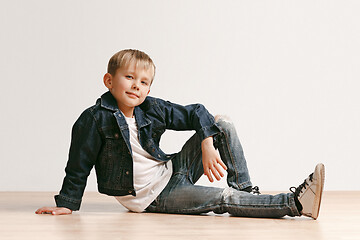 Image showing The portrait of cute little boy in stylish jeans clothes looking at camera at studio