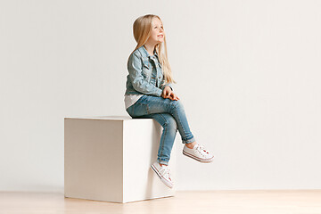 Image showing The portrait of cute little kid in stylish jeans clothes looking at camera and smiling