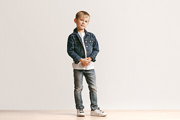 Image showing The portrait of cute little boy in stylish jeans clothes looking at camera at studio