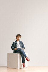 Image showing The portrait of cute little boy in stylish jeans clothes looking at camera at studio