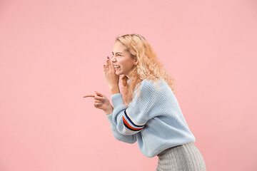 Image showing The young woman whispering a secret behind her hand over pink background