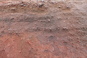 Image showing A cut of soil with rocks and red soil