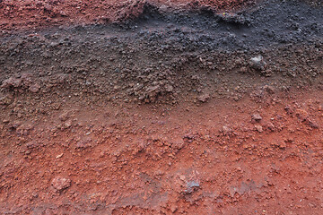 Image showing A cut of soil with rocks and red soil