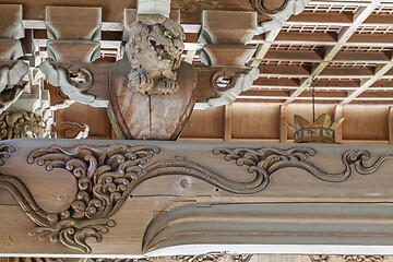 Image showing Wooden carving of an angry Komainu decorates the gable of a roof over the entrance of an ancient Buddhist temple in Japan.