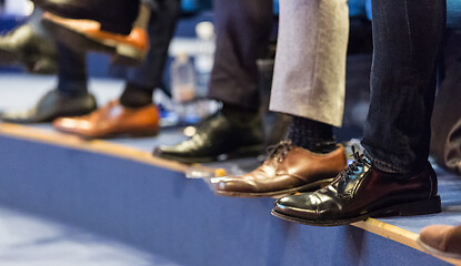 Image showing Detail of row of men\'s formal corporate business shoes. Business people sitting at seminar.