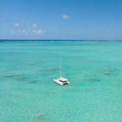 Image showing Catamaran sailing boat in turquoise sea lagoon on tropial Mauritius island. Aerial, drone view.