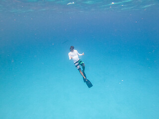 Image showing Underwater view of man free diving in blue ocean.