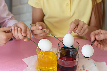 Image showing Hands dip chicken eggs in a dye solution