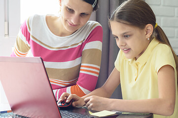 Image showing Girl learns to work on the Internet, mom helps her