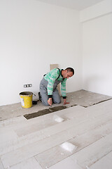 Image showing worker installing the ceramic wood effect tiles on the floor