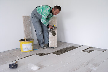 Image showing worker installing the ceramic wood effect tiles on the floor