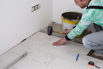 Image showing worker installing the ceramic wood effect tiles on the floor