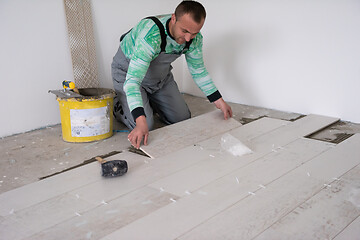 Image showing worker installing the ceramic wood effect tiles on the floor