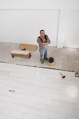 Image showing worker installing the ceramic wood effect tiles on the floor