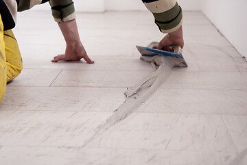 Image showing Tilers filling the space between ceramic wood effect tiles